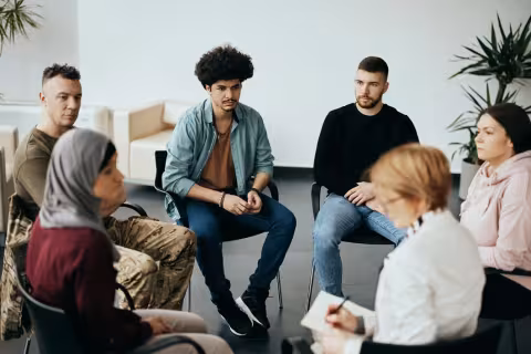 Multi-ethnic participants on group therapy having meeting with their psychotherapist at community center