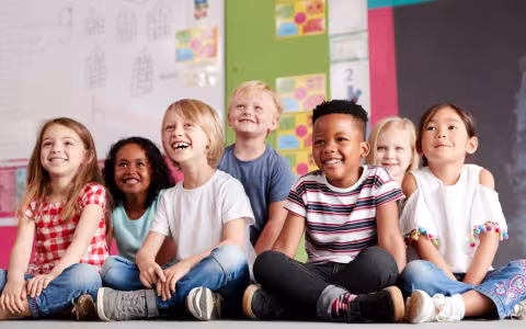 Group Of Elementary School Pupils Sitting On Floor In Classroom