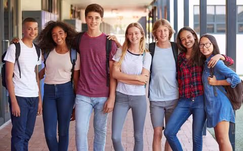 Teenage classmates standing in high school hallway