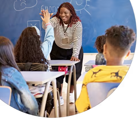 Teacher and schoolgirl exchanging high-five in classroom