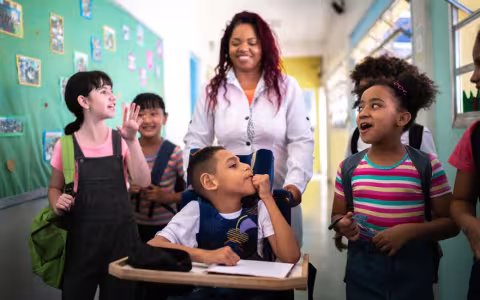 Teacher and students walking in the corridor at school - including a person with special needs