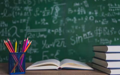 Books and blackboard on wooden background.